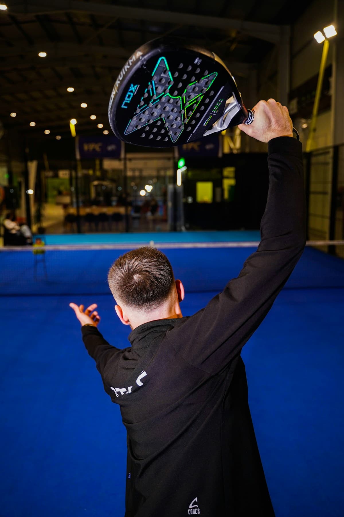 Giocatore con racchetta da padel in mano su campo indoor